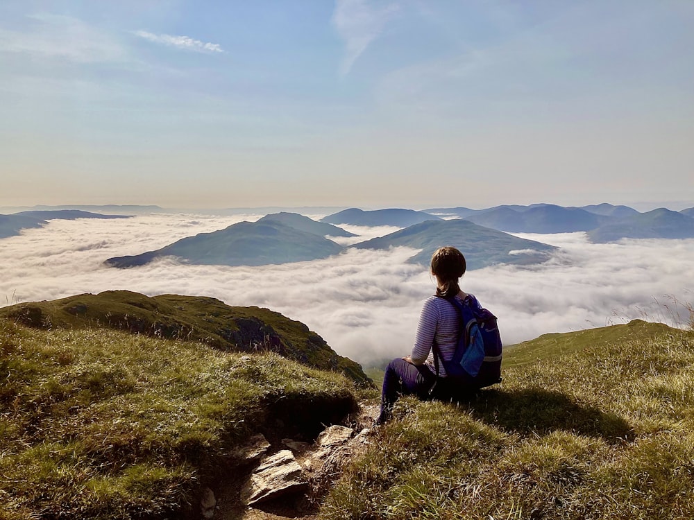 a woman sitting on top of a lush green hillside