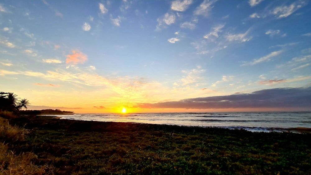 the sun is setting over the ocean on the beach