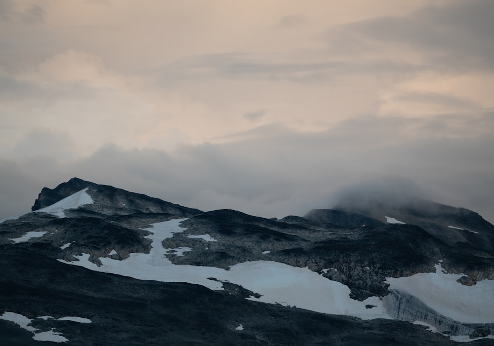 a mountain covered in snow under a cloudy sky