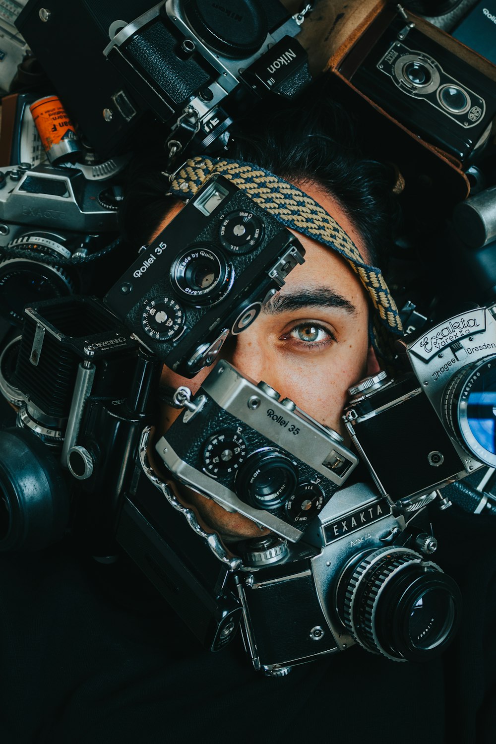a man is hiding behind a pile of cameras
