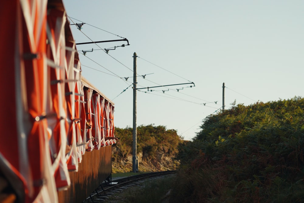 a train traveling down train tracks next to a lush green hillside