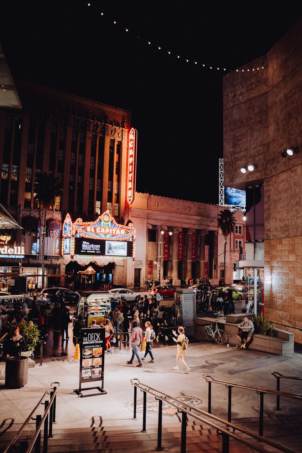 a crowd of people walking around a city at night