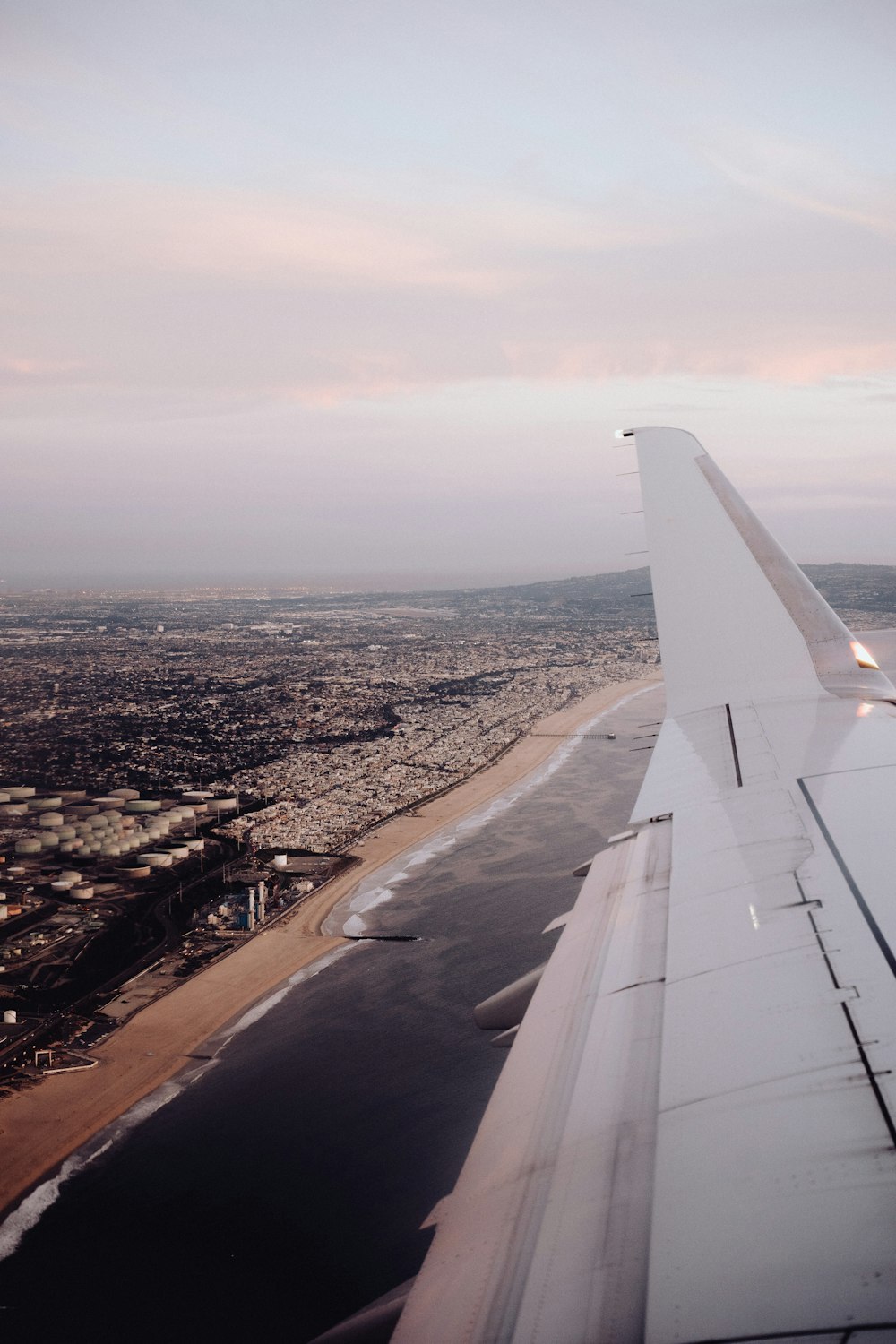 a asa de um avião voando sobre uma cidade