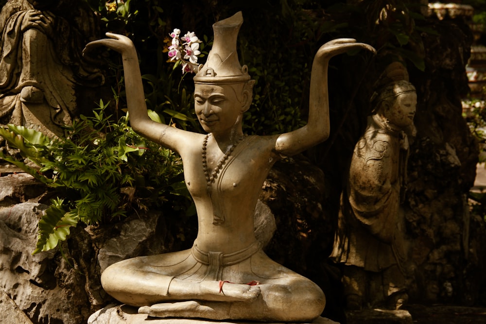 a statue of a woman sitting on top of a rock