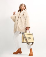 a woman in a fur coat holding a fendi bag