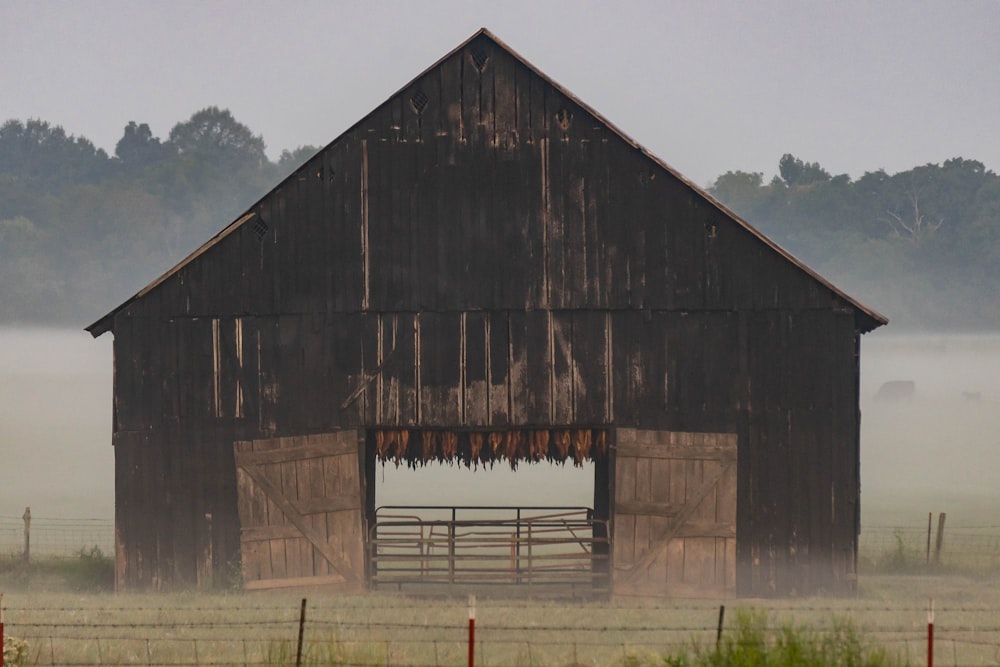 a barn in the middle of a foggy field