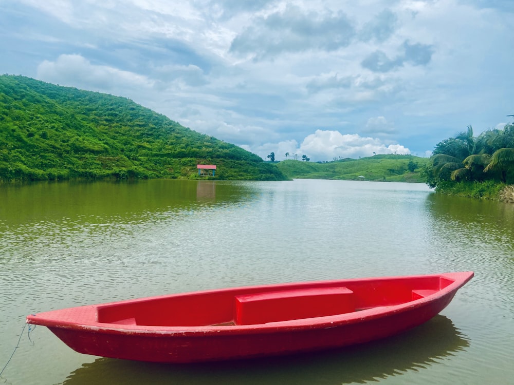 a red boat floating on top of a lake