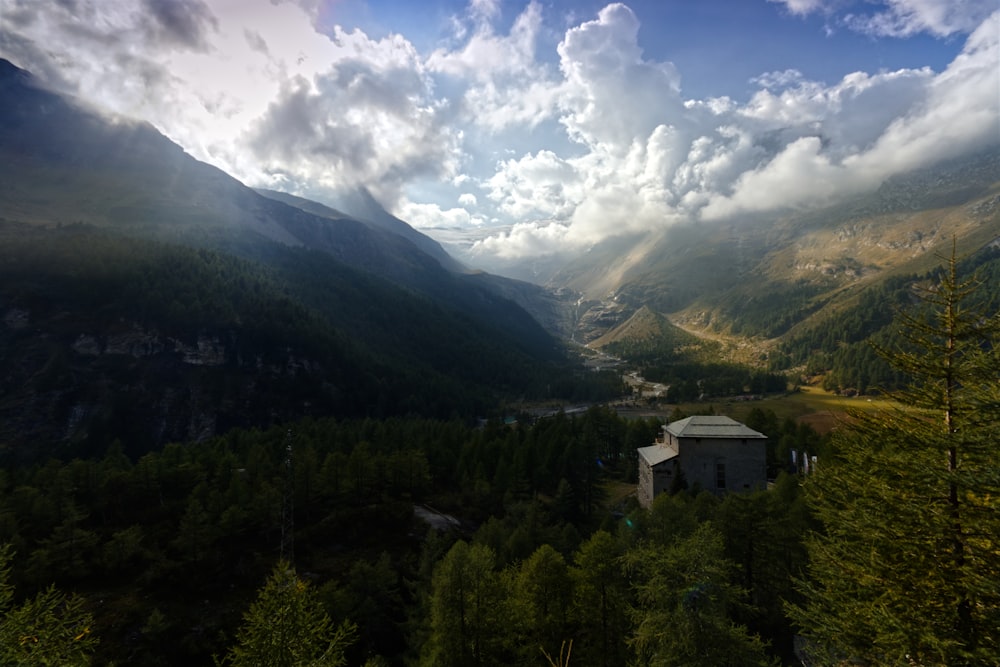 a scenic view of a mountain valley with a building in the foreground