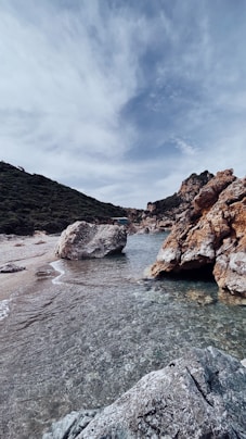 a body of water surrounded by rocks under a cloudy sky