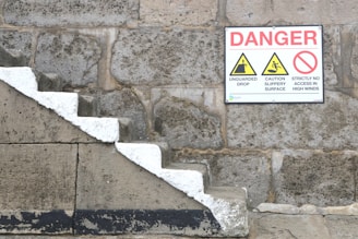 a sign on a stone wall warning of danger