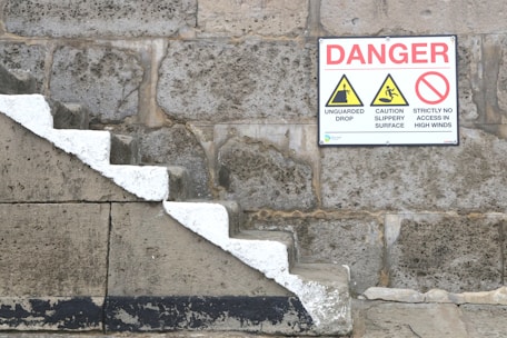a sign on a stone wall warning of danger