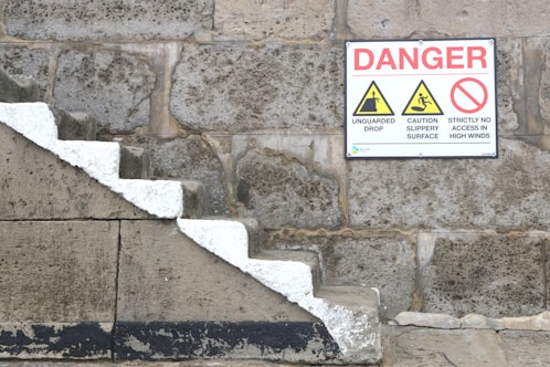 a sign on a stone wall warning of danger