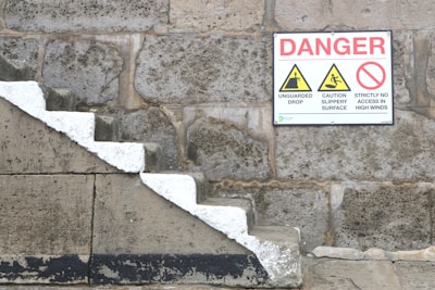 a sign on a stone wall warning of danger