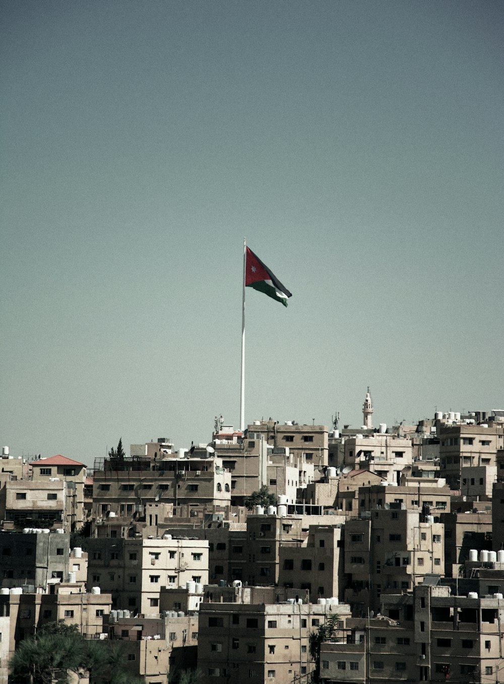 a flag flying over a city with lots of buildings