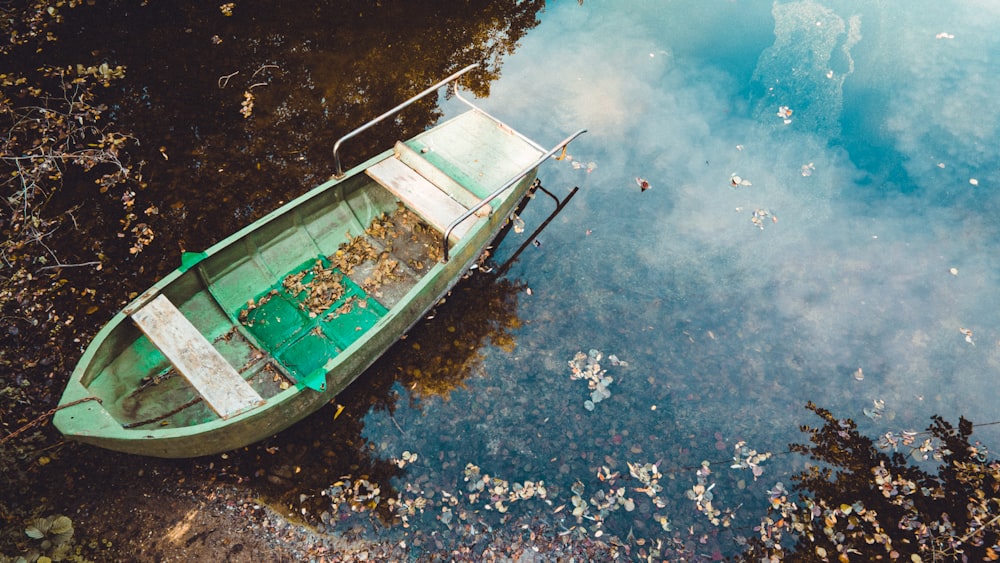 a small green boat floating on top of a body of water