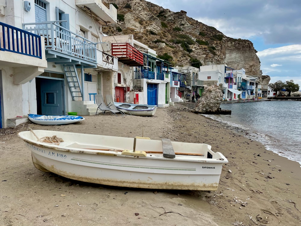 a white boat sitting on top of a sandy beach