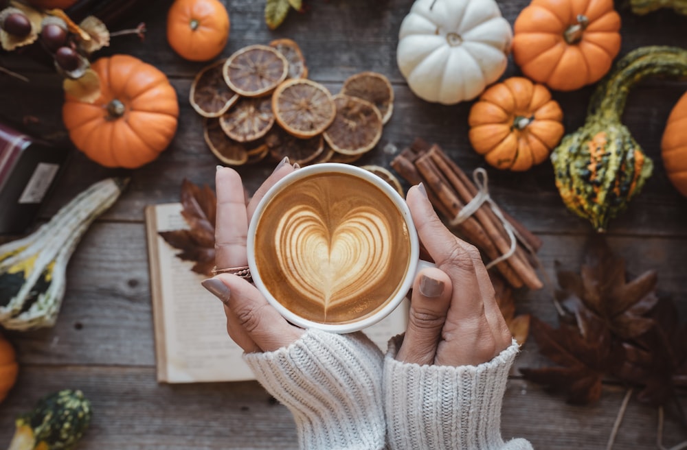 una persona che tiene una tazza di caffè con un cuore su di esso