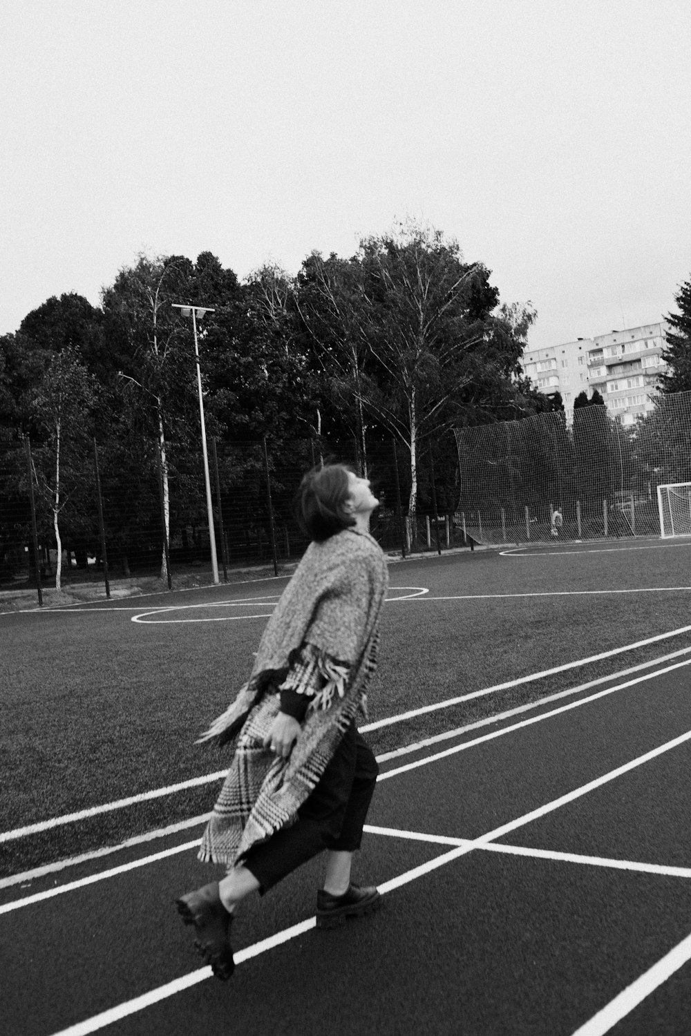 a woman walking across a parking lot next to a soccer field