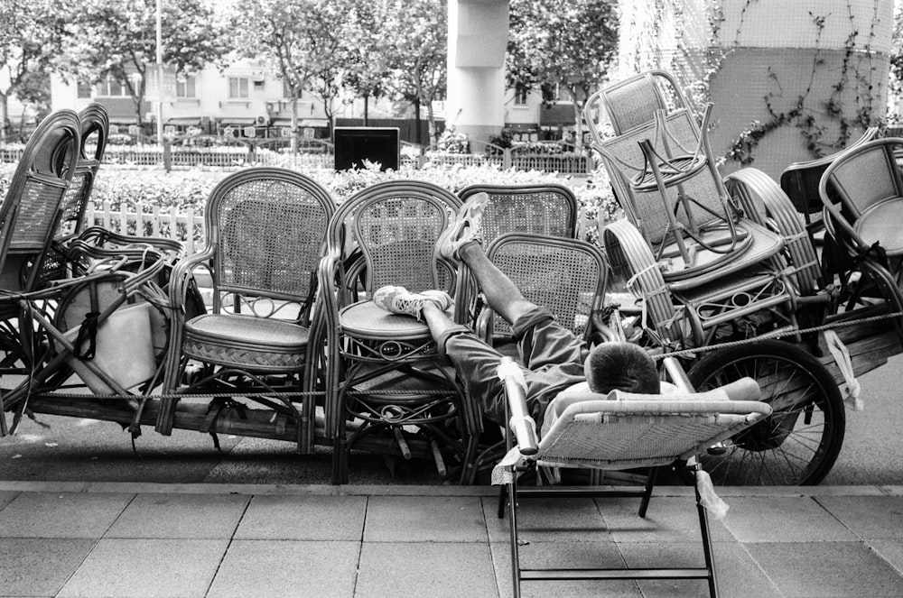 a black and white photo of a person laying on a lawn chair next to a