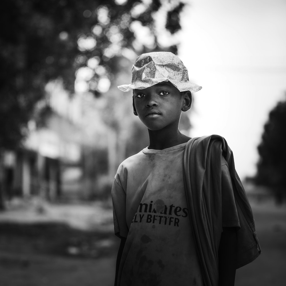 a black and white photo of a young boy wearing a hat