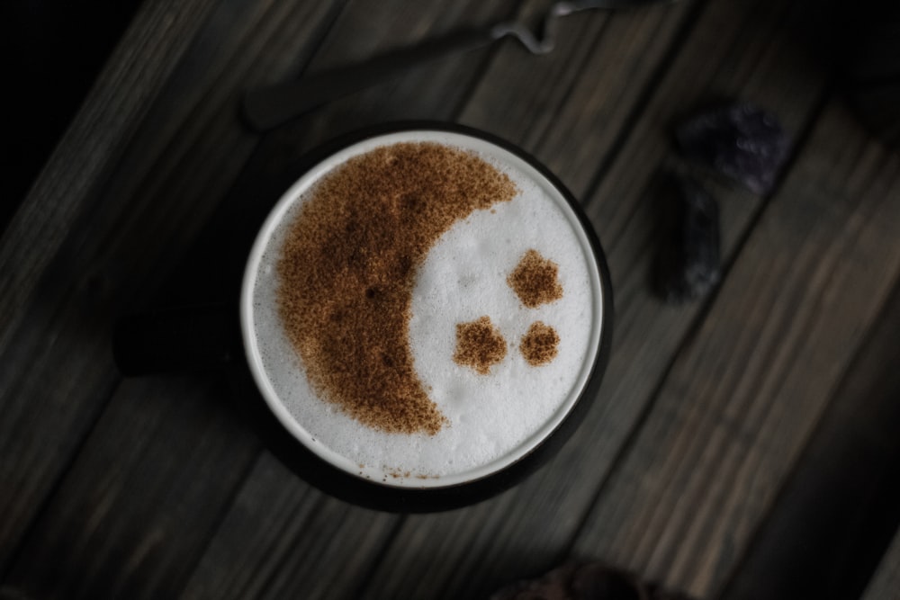 uma xícara de café com um rosto sorridente desenhado sobre ele