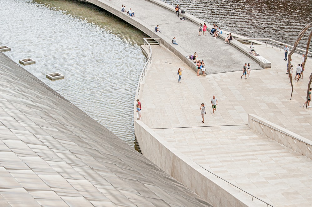 a group of people walking along a river next to a bridge