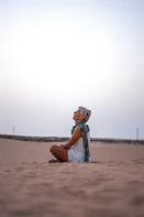 a woman sitting on the ground in the sand