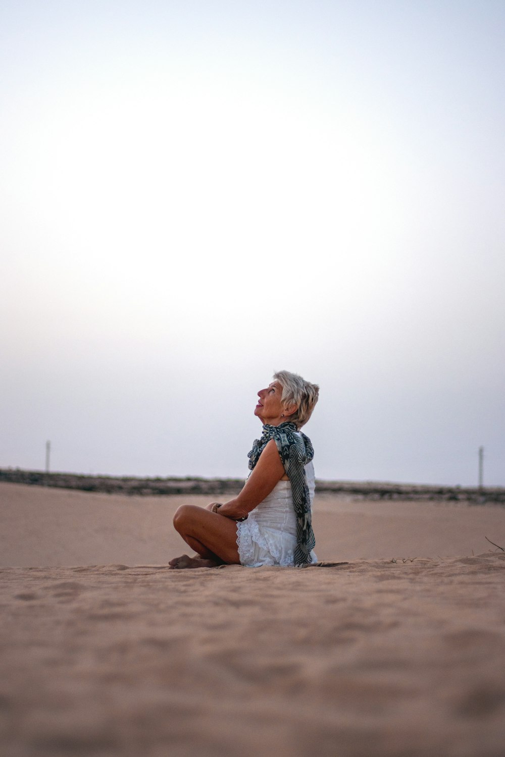 a woman sitting on the ground in the sand