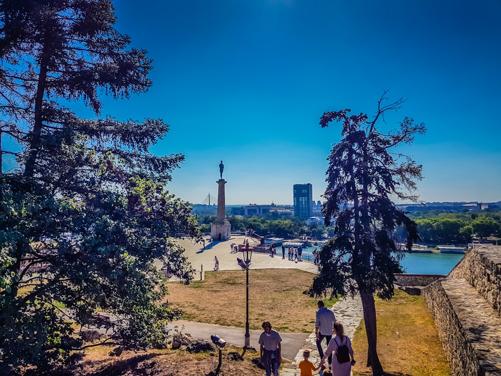 a group of people walking up a hill next to a river