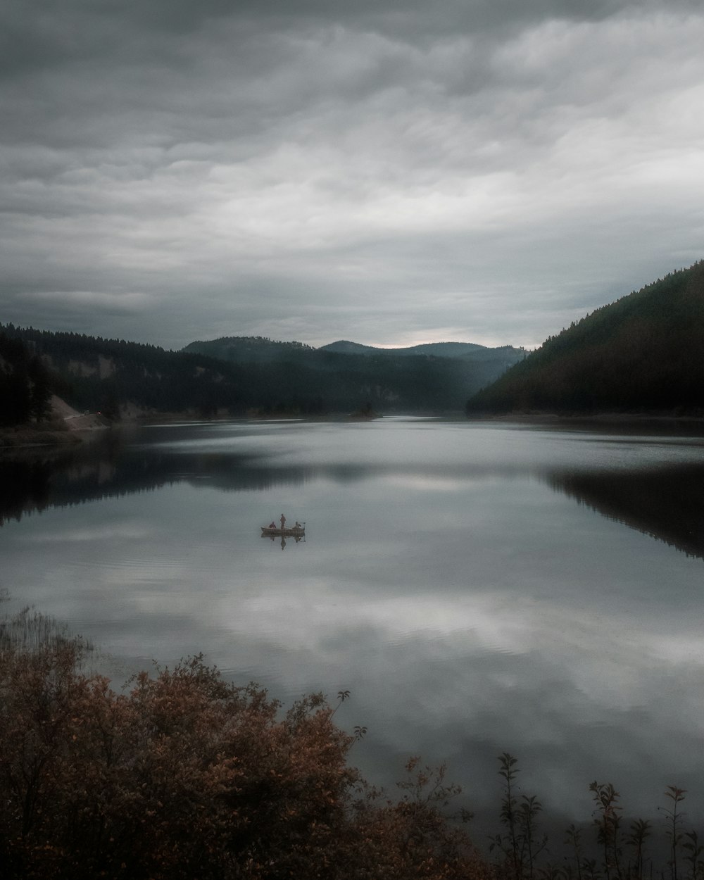 a boat floating on top of a lake under a cloudy sky