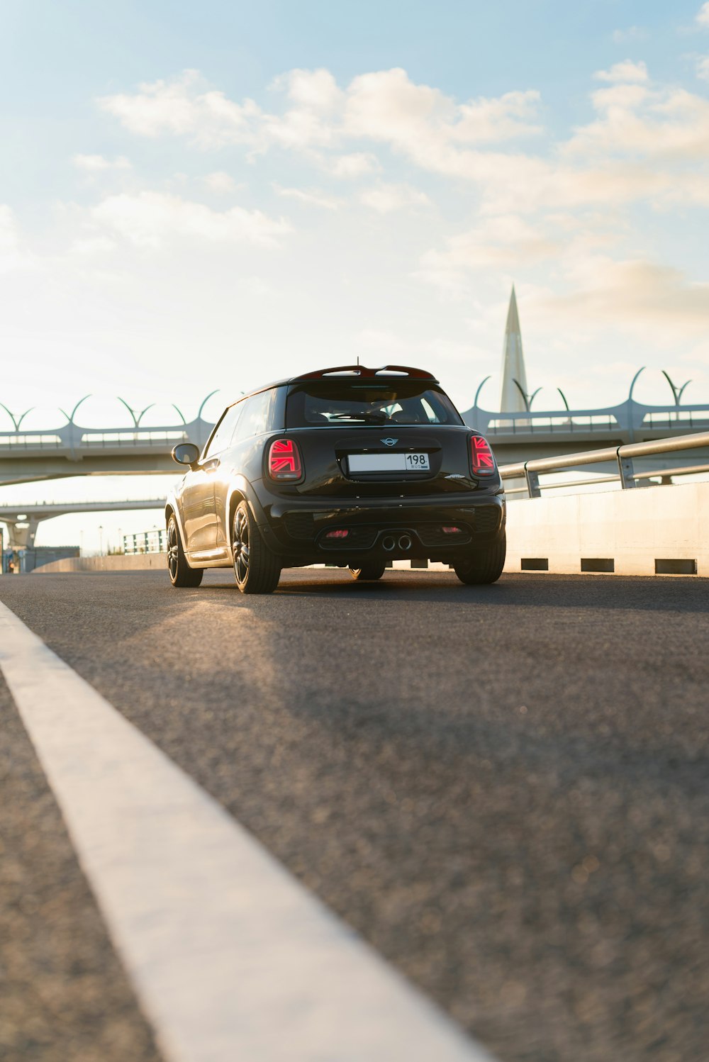 a black car driving down a road next to a bridge