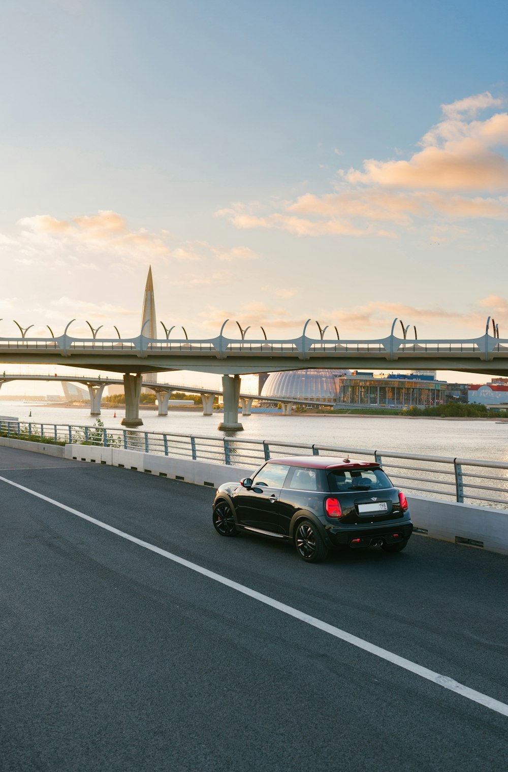 Ein schwarzes Auto, das neben einer Brücke eine Autobahn hinunterfährt