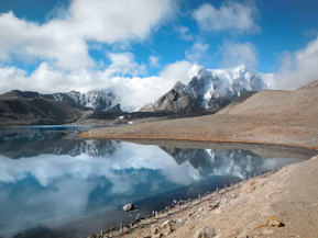 a lake surrounded by mountains under a cloudy sky