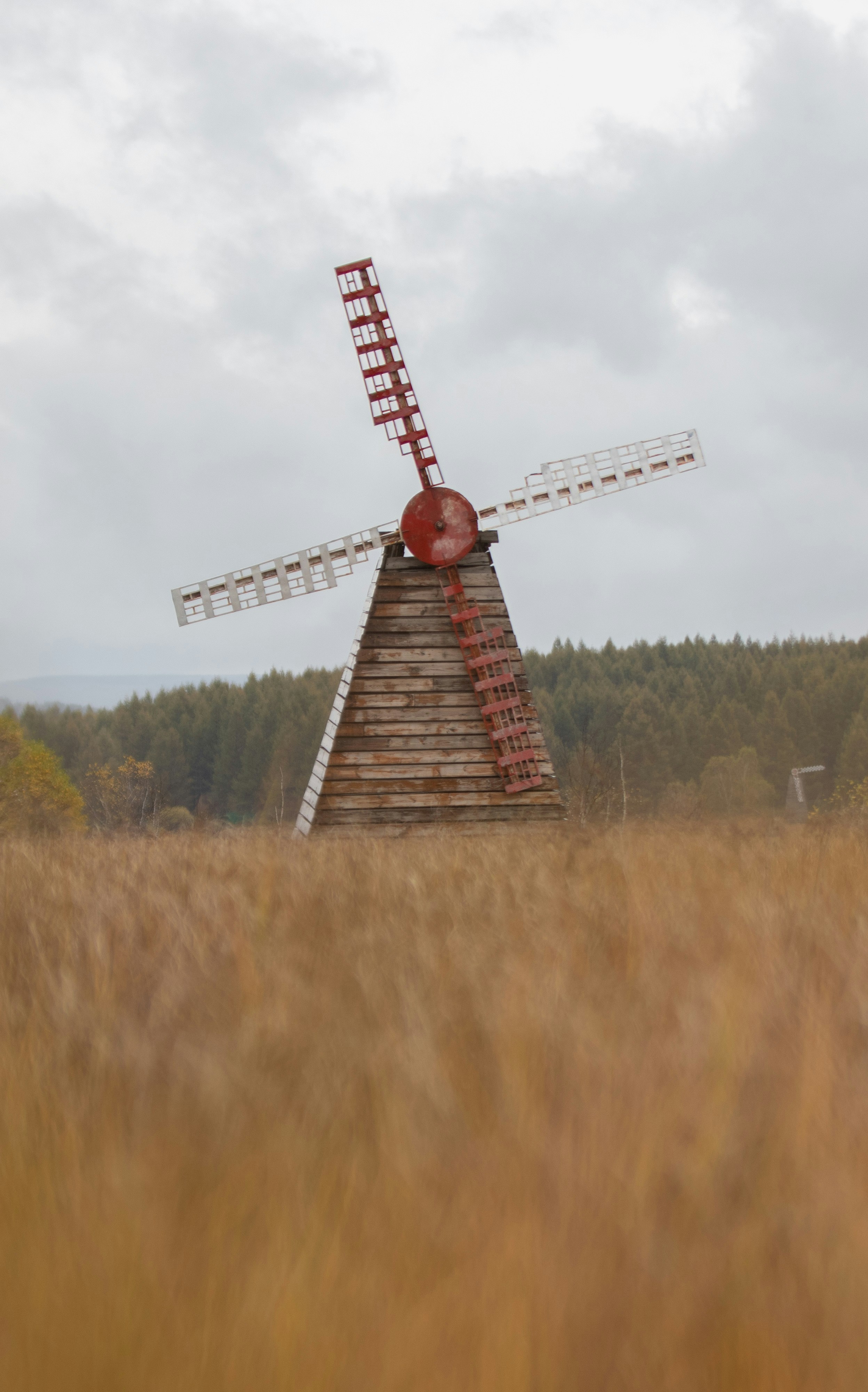 a windmill in a field with trees in the background