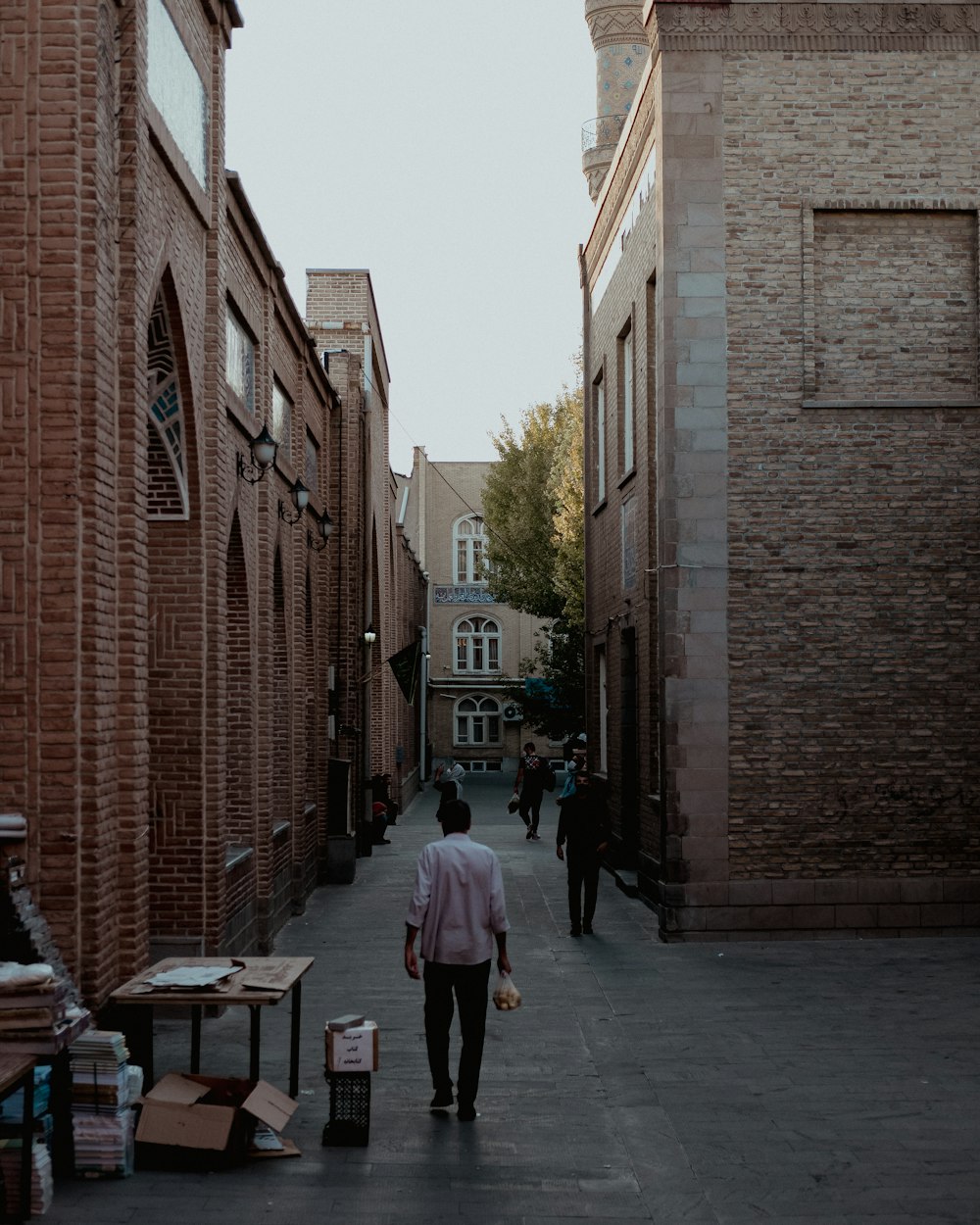 a man walking down a street next to tall brick buildings