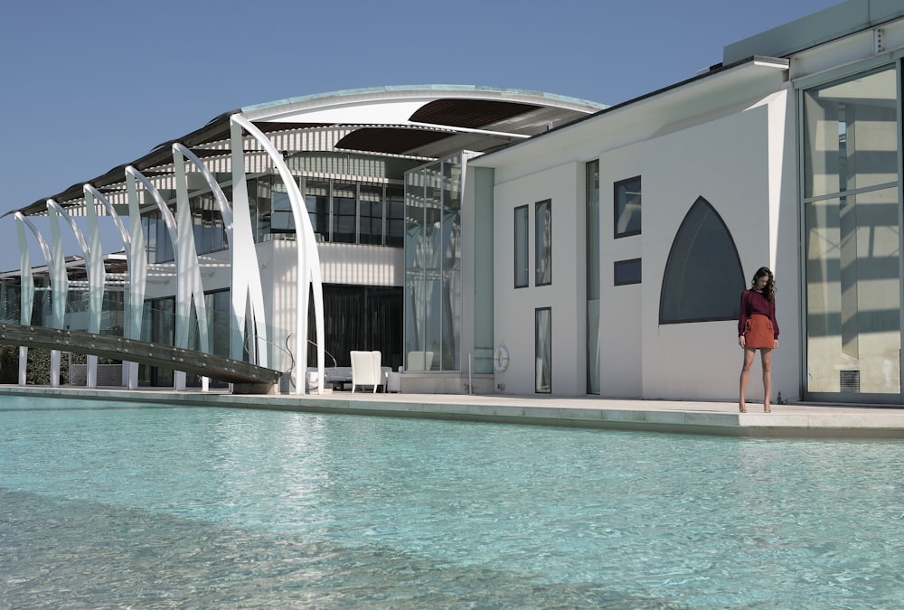 a woman standing in front of a building next to a pool