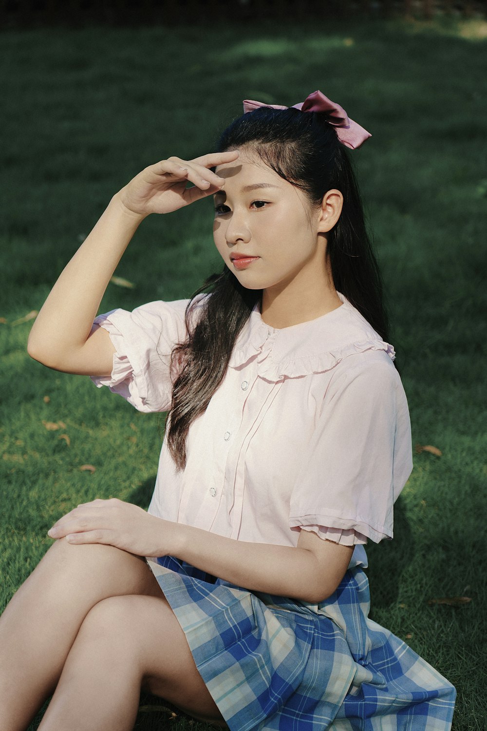 a woman sitting in the grass with her hand on her head