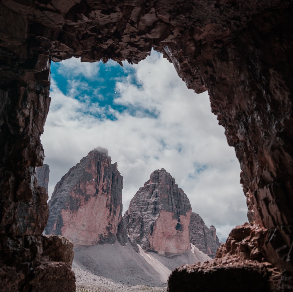 a view of a mountain range through a hole in a rock formation