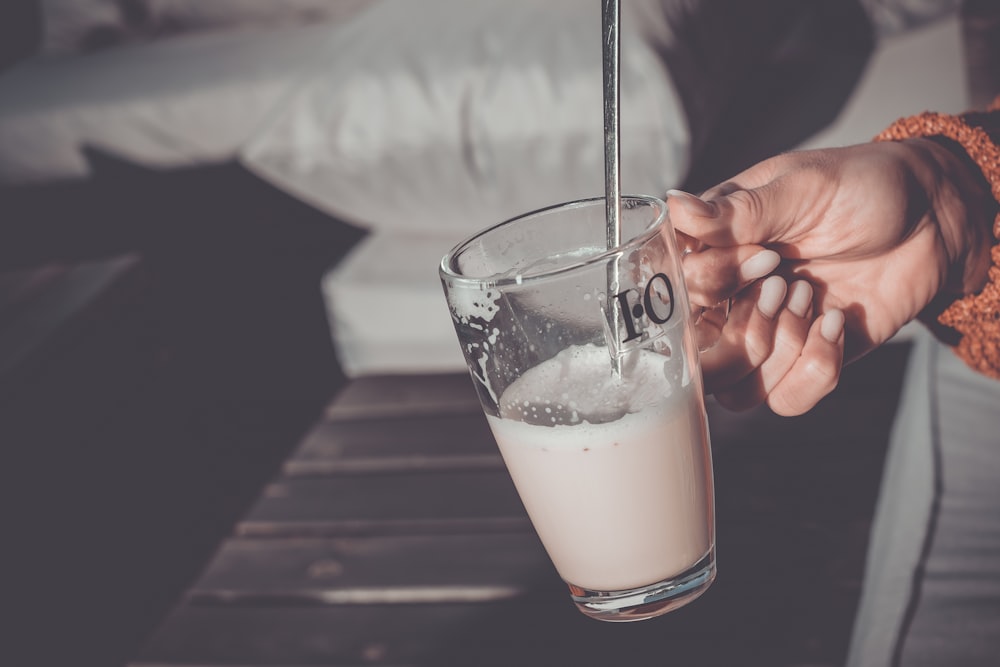 a person is holding a glass of milk
