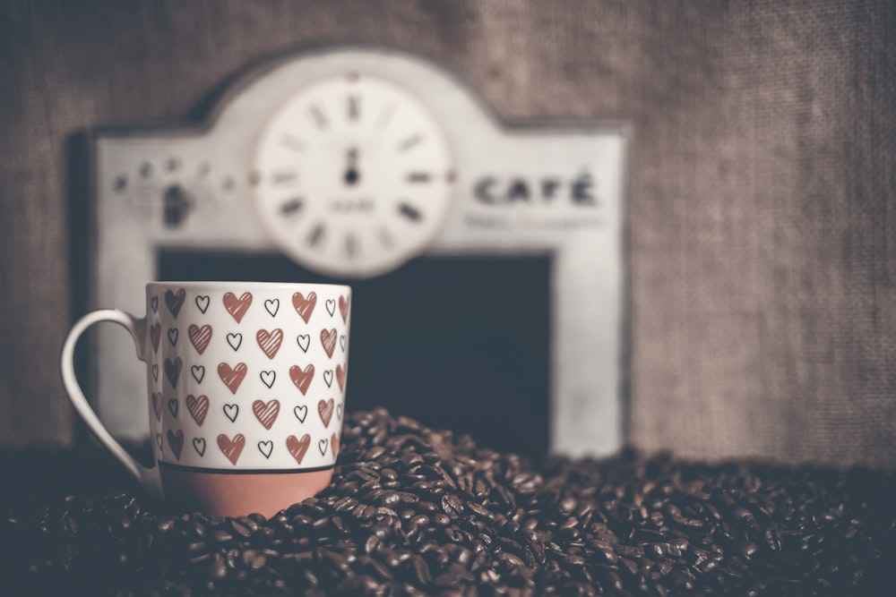 a coffee cup sitting on top of a pile of coffee beans