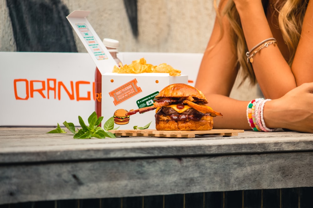 a woman sitting at a table with a box of food in front of her