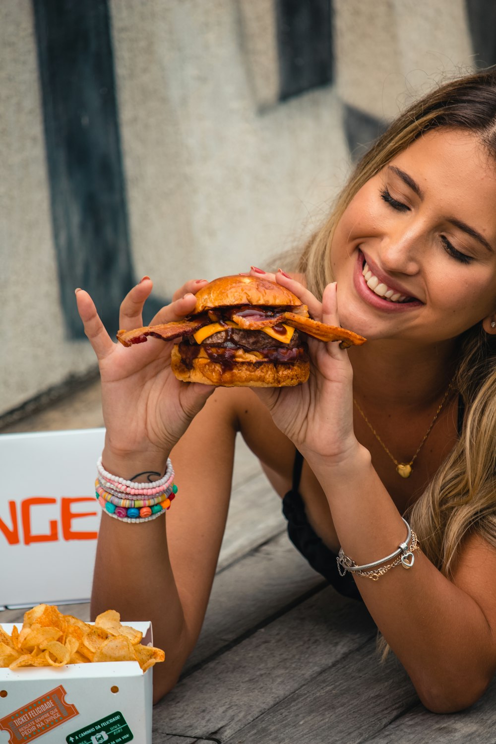 a woman eating a giant cheeseburger with a smile on her face