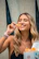 Smiling woman holding a bag of Crunchips plantain snacks in a vibrant Colombian market.