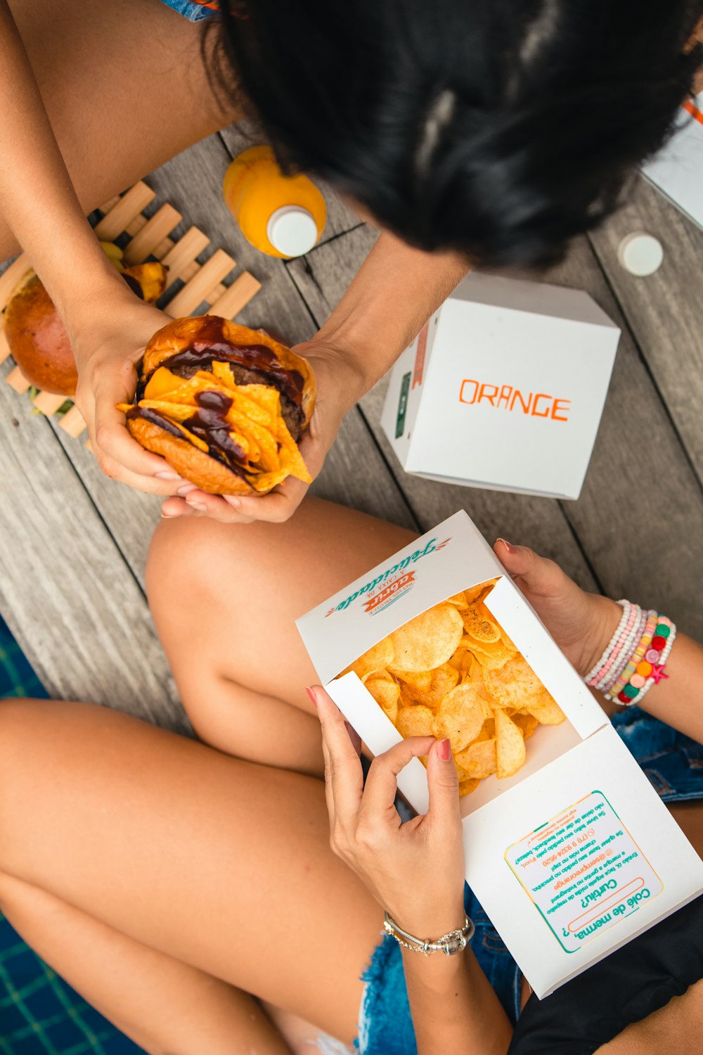 a woman holding a box of food and a box of chips