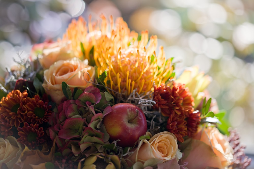 a bouquet of flowers and apples on a table