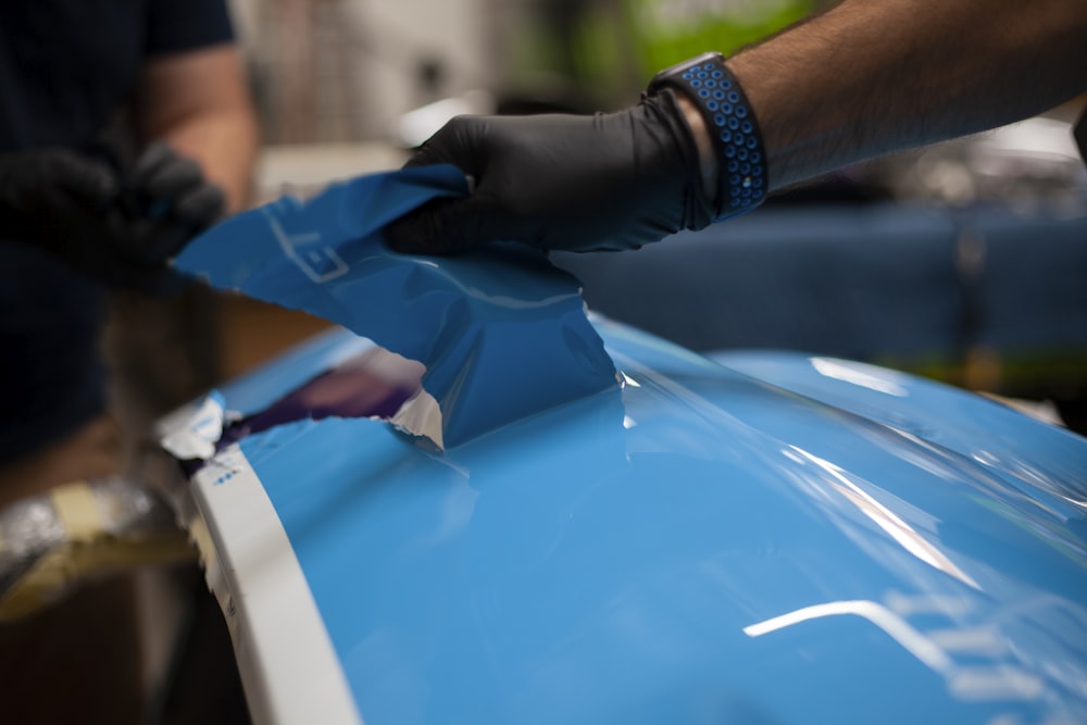 a person wearing gloves and gloves is painting a blue car