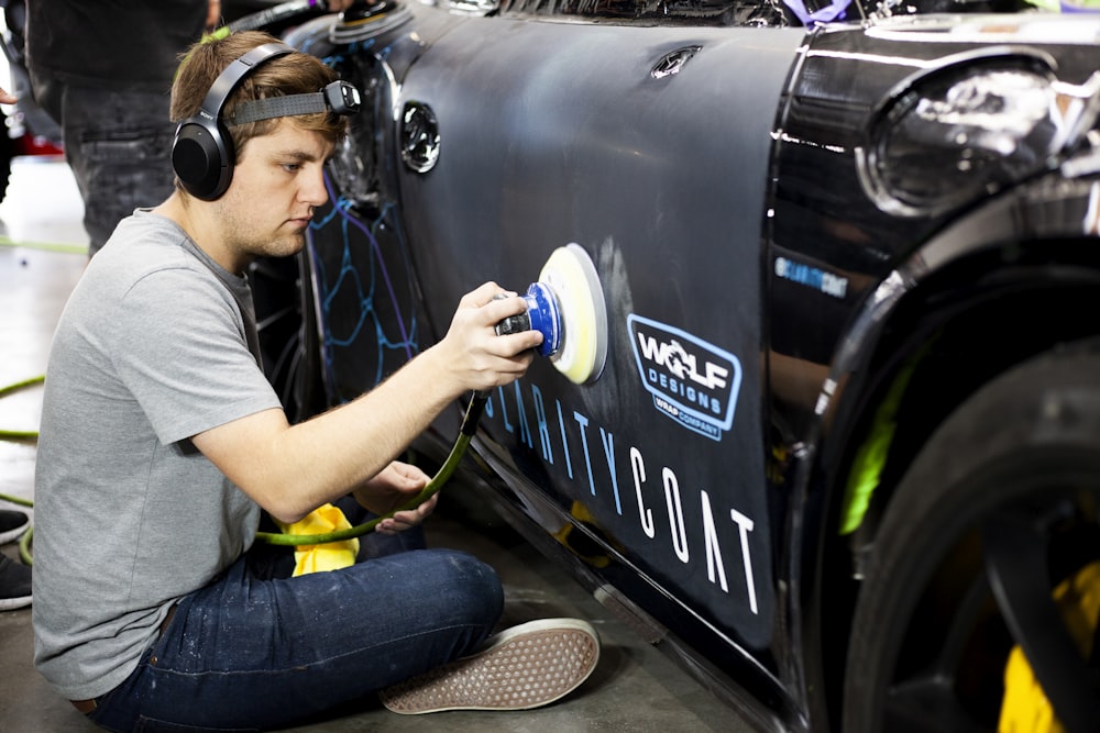 a man is painting a car with a spray gun