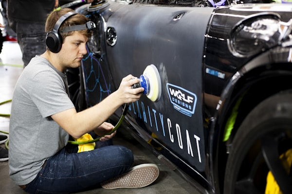 Man spray painting a Porsche in auto body shop
