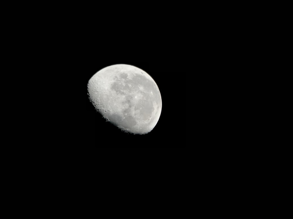 a full moon is seen in the dark sky