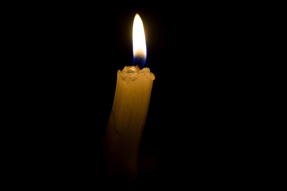 a lit candle in the dark with a black background